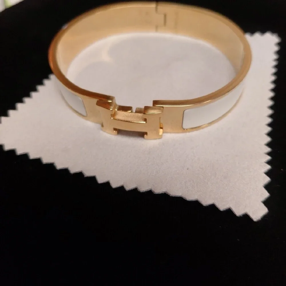 HERMES Gold and White Enamel Click H Bracelet with Signature H Accent.